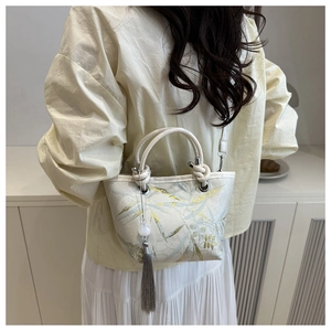 Close-up of bamboo embroidery and silk texture on elegant crossbody bucket bag