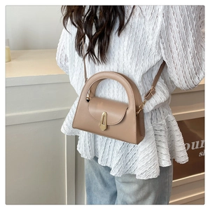 Detail view of khaki leather handbag featuring gold trapezoidal buckle and sleek handle