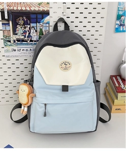 Detailed view of tricolor nylon backpack with plush toast pendant and multi-pocket design