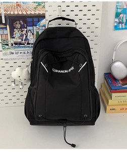 Detail view of black nylon backpack with white logo and plush cloud charm on pegboard