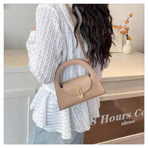 Detail of beige semicircular handbag with gold metal clasp and minimalist smooth texture