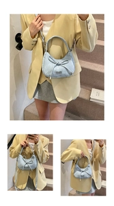 Detail of light blue crescent bag featuring a decorative bow knot and metallic brand logo