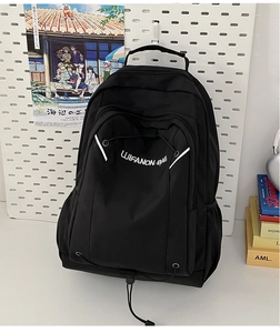 Detail of black nylon backpack featuring white logo embroidery and front storage pockets