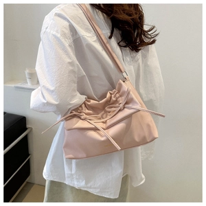 Detail of pink pleated soft leather tote bag with bow drawstring worn by a model