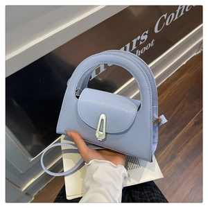 Close-up of the light blue leather handbag featuring a golden geometric metal twist lock