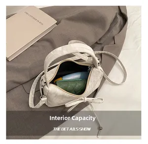 Détail de la capacité intérieure d'un chic sac à main blanc avec nœud et objets quotidiens