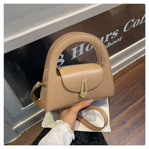 Macro view of apricot leather handbag featuring a round handle and gold geometric clasp