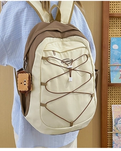 Détail du sac à dos contrasté avec cordons élastiques et breloque biscuit en peluche