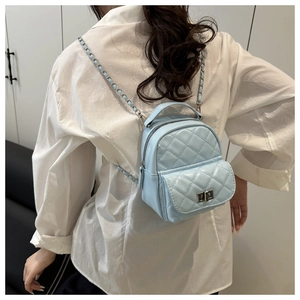 Rear view of a light blue quilted mini backpack featuring silver chain straps on a model