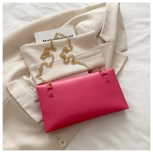 Detail of rose pink envelope bag with golden chain strap on beige blazer