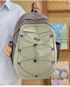 Détail du sac à dos gris et vert avec cordons élastiques et pendentif en peluche