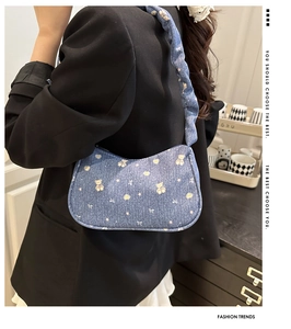 Détail du sac sous l'aisselle en denim bleu avec motifs d'ours et bandoulière plissée