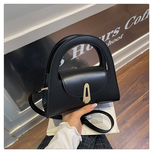Detail of black semi-circular handbag with silver geometric lock and large handle