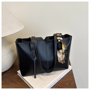 Detail of black leather tote bag featuring contrast stitching and floral silk scarf accessory