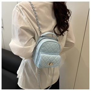 Rear view of a model wearing a mini light blue quilted leather backpack with silver chains