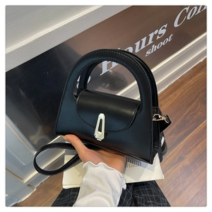 Detailed view of the silver geometric lock on a black semi-circular crossbody bag