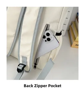 Close-up of anti-theft back zipper pocket on a cream backpack with smartphone storage