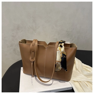 Detail of dark brown tote bag with contrast stitching and patterned silk scarf handle