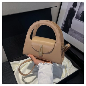 Close-up of khaki leather handbag with semi-circular handle and gold metal lock in a gift box
