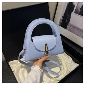 Detail of light blue semi-circular handbag with golden lock and smooth leather texture