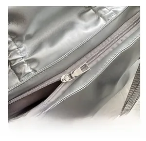 Macro shot of smooth metal zipper and gray fabric lining on a silver PU shoulder bag