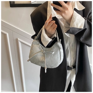 Close-up of light blue pleated handbag featuring a bow tie and silver metal logo detail