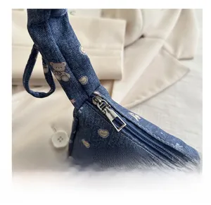 Détail de la fermeture éclair argentée et des coutures sur le sac à main en denim bleu