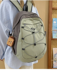 Détail du sac à dos en nylon vert et gris avec cordon élastique et breloque biscuit peluche