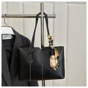 Detail of black faux leather tote bag with white contrast stitching and printed silk scarf