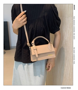 Detail view of beige crossbody bag with gold logo and elegant flap closure