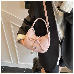 Détail d'un sac à main rose avec nœud, logo en argent et finition en cuir texturé