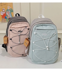 Détail de sacs à dos légers rose et bleu avec laçage et jolis pendentifs de décoration
