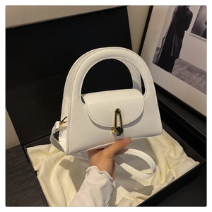 Detail of white semi-circle handbag with gold geometric lock in elegant gift box