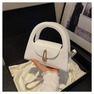 Detail of a white semicircular handle handbag with a gold shield lock in a gift box