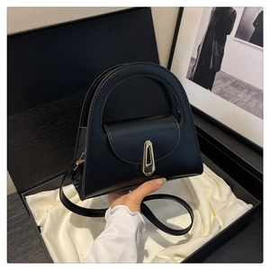 Detail of black leather handbag with gold geometric clasp in luxury gift box