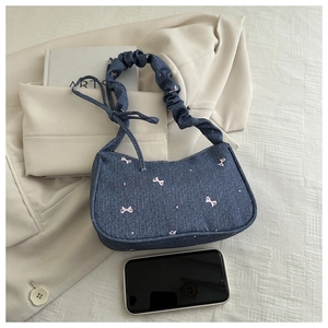 Gros plan du sac hobo en jean bleu avec broderie nœud rose et poignée à volants