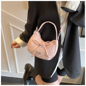 Sac demi-lune rose avec nœud porté sur un blazer noir pour un look élégant et moderne
