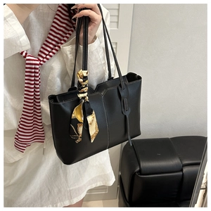 Detail of black leather tote bag with white contrast stitching and floral silk scarf accessory