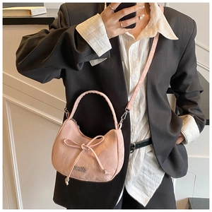Detail of pink pleated crossbody bag with bow decoration and silver logo on model