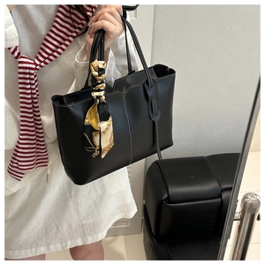 Detail of black tote bag with white contrast stitching and printed yellow silk scarf accessory