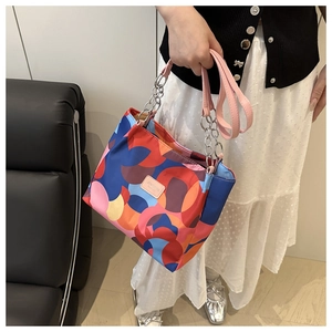 Detail of waterproof nylon tote with colorful geometric dots and pink leather handles