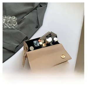 Detail showing internal capacity of the beige leather crossbody bag with items inside