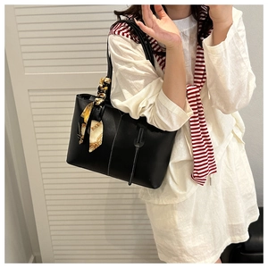 Close-up of black tote bag with white stitching and silk scarf on shoulder