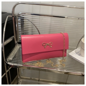 Detail of rose pink envelope bag with golden bow clasp and delicate chain strap