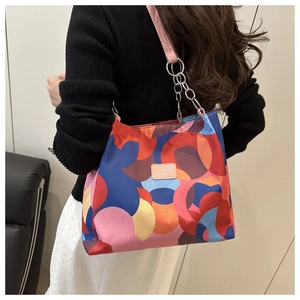 Detail of colorful geometric pattern handbag with pink leather strap and silver chain