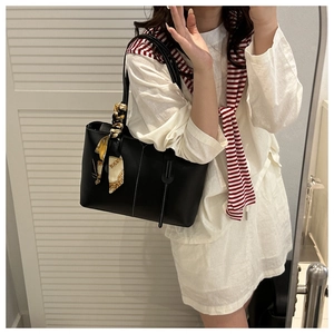 Detailed view of black matte leather tote bag with white stitching and silk scarf