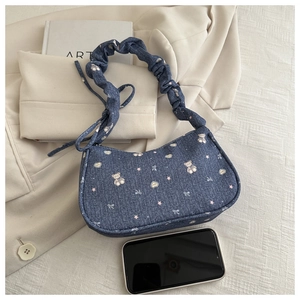 Détail du sac à épaule en denim avec imprimés cartoon et bandoulière froncée avec mobile