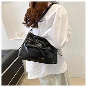 Detailed view of black pleated cloud bag with ribbon bows and fashion logo lettering