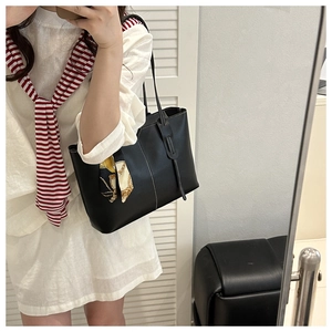 Detail of black leather tote bag with white contrast stitching and decorative silk scarf