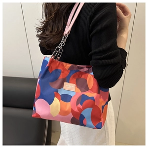 Detail of colorful geometric pattern and pink leather strap with silver chain on shoulder bag
